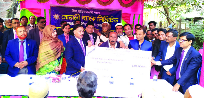 Md Ataur Rahman Prodhan, CEO & Managing Director of Sonali Bank Ltd, handing over a cheque to ailing freedom fighter Md Dabir Uddin Ahmed at Rasulganj of Patgram upazila in Lalmonirhat on Friday. Local adminstration officials and the bank's executives we