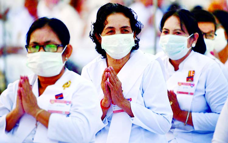 Women pray while wearing face masks at Wat Phra Dhammakaya temple during a ceremony to commemorate Makha Bucha Day outside Bangkok, Thailand. Internet photo