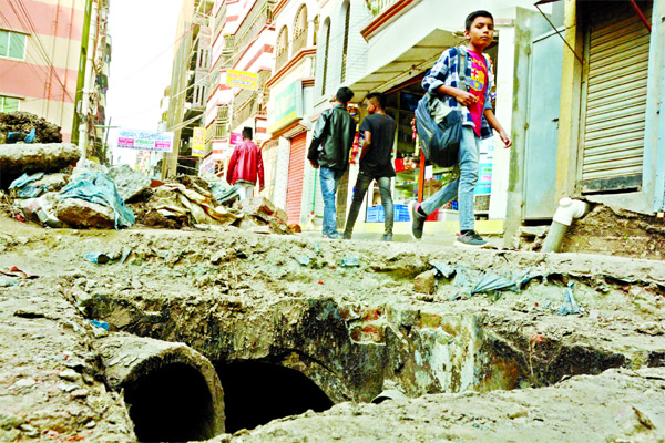 Several key roads have been dug up in Dhaka for laying utility lines given rise to commuting perilous for local dwellers. This photo taken on Sunday shows that pedestrians pass through a big ditch created on Rampura main road.