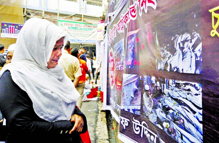 One year of Chawkbazar Tragedy: A relative of Churihatta fire victim breaks down in tears after seeing photos of the deceased hang on a wall at Churihatta in Dhaka on Thursday making the first anniversary of the tragic incident.