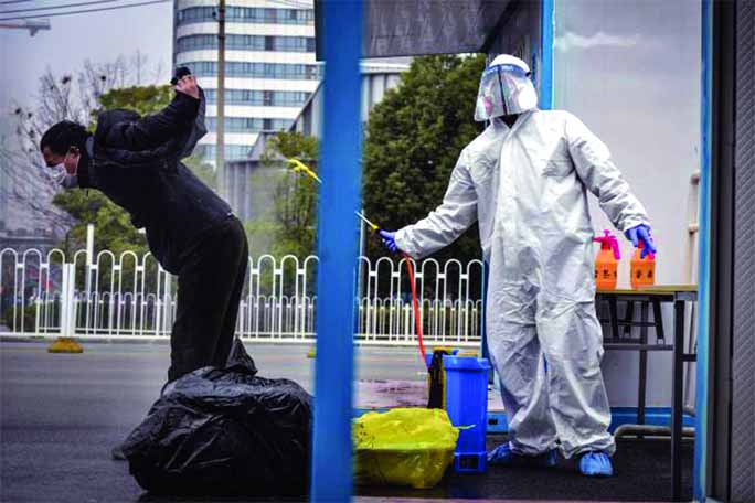 Photo shows a man (L) who has recovered from the COVID-19 coronavirus infection being disinfected by a medical staff before leaving the hospital in Wuhan in China's central Hubei province.