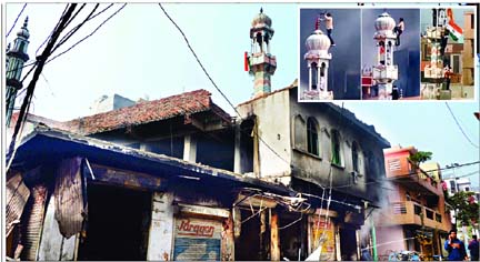 The mosque was set on fire in the Indian capital on Tuesday by Hindu mobs. (Inset) a mob climbing to the top of the mosque's minaret where they were planting Hanuman flag.