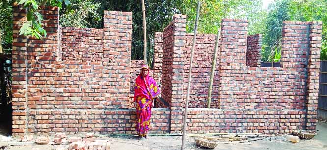 KISHOREGANJ (Nilphamari): Jannati Begum at Masterpara Village in Putimari Union of Nilphamari Upazila standing beside her house given by Rural Infrastructure Development Project in 2019- 2020 fiscal year recently.