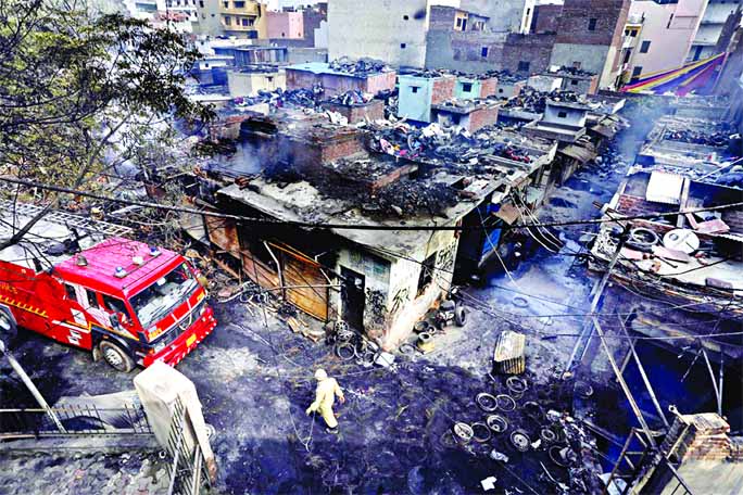 A firefighter walks past damaged shops at a tyre market after they were set on fire by a mob in a riot affected area after clashes erupted between people demonstrating for and against a new citizenship law in New Delhi.