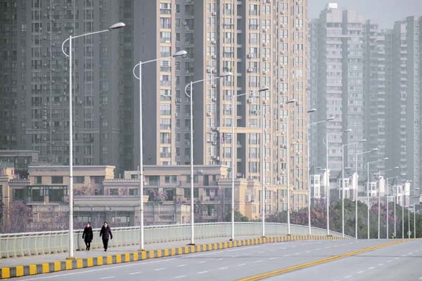 People wearing face masks walk down a deserted street in Wuhan in central China's Hubei Province. As the coronavirus spreads around the world, International health authorities are hoping countries can learn a few lessons from China, namely, that quaranti