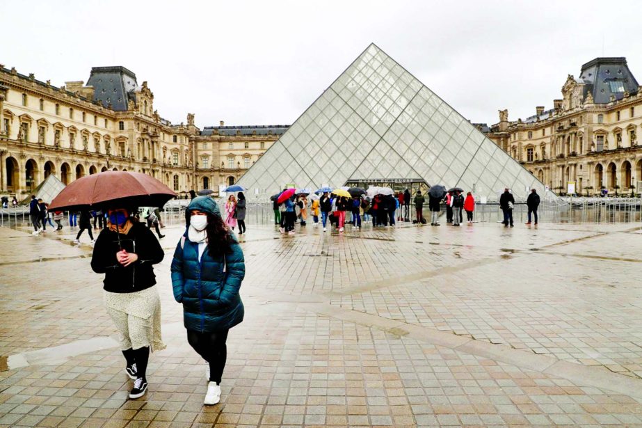 Two people walk away from the Pyramid, the main entrance to the Louvre museum which was once a royal residence, located in central in Paris.