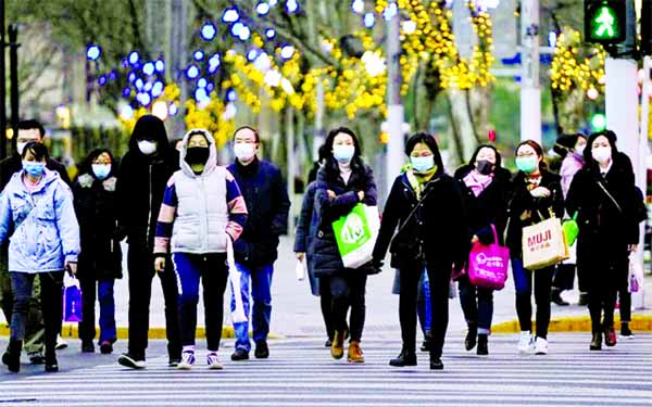 People wearing protective face masks walk at a crossroads as the country is hit by an outbreak of the novel coronavirus, in Shanghai, China on Thursday.