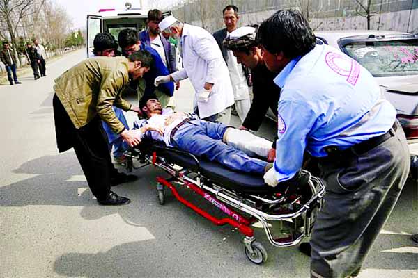 A wounded man in Kabul clasping his abdomen on a stretcher is helped by locals and a doctor.