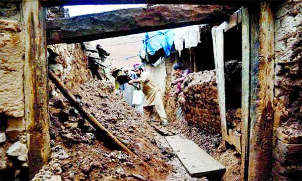 Residents remove debris from a damaged house after heavy rains in Peshwar.