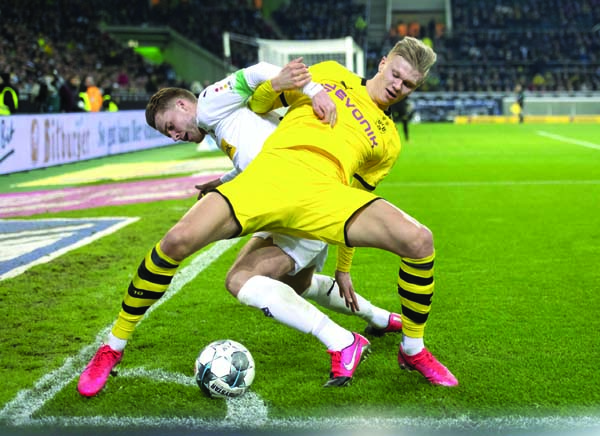Dortmund's Erling Haaland (front) battles for the ball during the Bundesliga soccer match between Borussia Monchengladbach and Borussia Dortmund, at Borussia Park in Monchengladbach of Germany on Saturday.