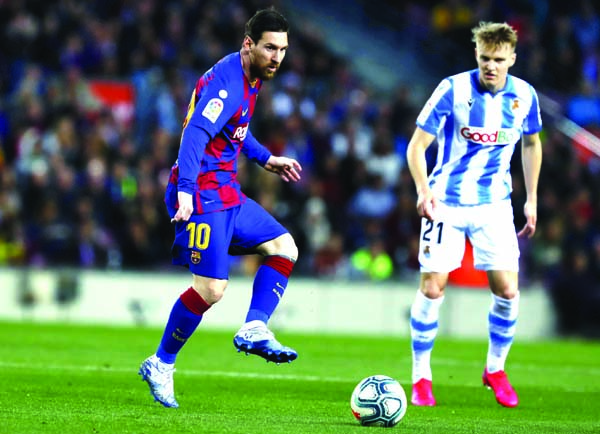Barcelona's Lionel Messi (left) plays the ball past Real Sociedad's Martin Oedegaard during a Spanish La Liga soccer match between Barcelona and Real Sociedad at the Camp Nou stadium in Barcelona of Spain on Saturday.