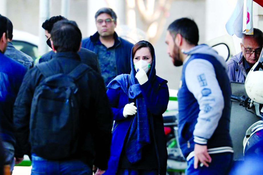 An Iranian woman wearing face mask walks on a street of Teheran.