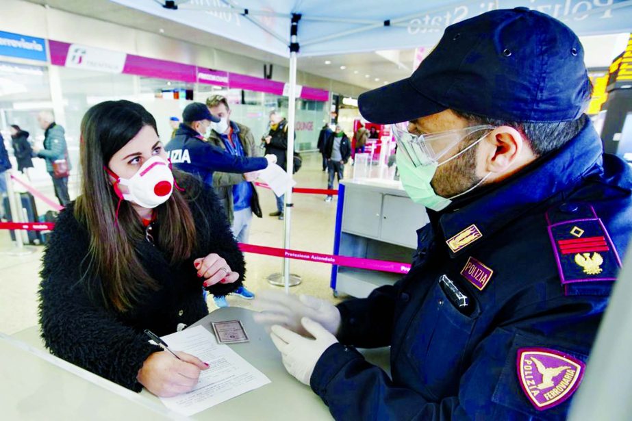 A traveller wears a mask as she fills out a form at a check point set up by border police inside Rome's Termini train station on Tuesday.