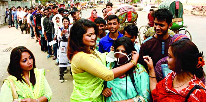 Bangamata Sanskritik Jote distributing coronavirus awareness mask free of cost in front of the National Museum on Thursday.