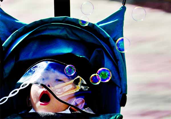 A boy wearing a hat with a protective screen, following an outbreak of coronavirus disease (COVID-19), blows soap bubbles at a park in Daegu, South Korea.