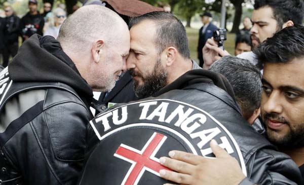Survivor of the Al Noor mosque shootings, Temel Atacocugu, center, exchanges a hongi with a member of the Tu Tangata motorcycle club outside the mosque in Christchurch, New Zealand on Sunday