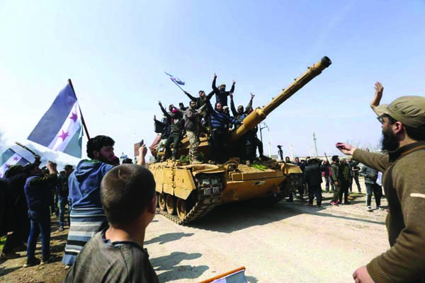 Syrians climb on a Turkish tank in Neyrab on Sunday as they protest agreement on joint Turkish and Russian patrols in northwest Syria. Patrols on the M4 highway, which runs east-west through Idlib province, are part of a cease-fire agreed between Turkey a