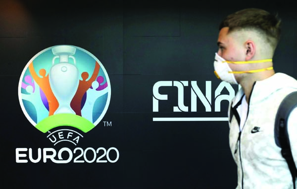 A traveller passes by a logo of the 2020 UEFA European Football Championship displayed on a wall inside Bucharest Henri Coanda International Airport in Otopeni of Romania on Tuesday.