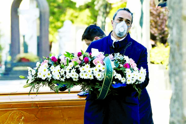 Cemetery workers and funeral agency workers in protective masks transport a coffin of a person who died from coronavirus disease (COVID-19), into a cemetery in Bergamo, Italy.