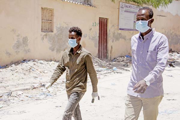 Somali men wear surgical masks on the street after the government announced the closure of schools and universities and banned large gatherings, following the announcement on Monday of the country's first case of the new coronavirus, in the capital Mogad