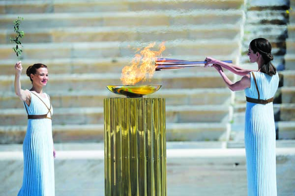 Greek actress Xanthi Georgiou dressed as an ancient Greek high priestess lights the Olympic torch as choreographer Artemis Ignatiou looks on during the Olympic flame handover ceremony for the 2020 Tokyo Summer Olympics, in Athens on Thursday.