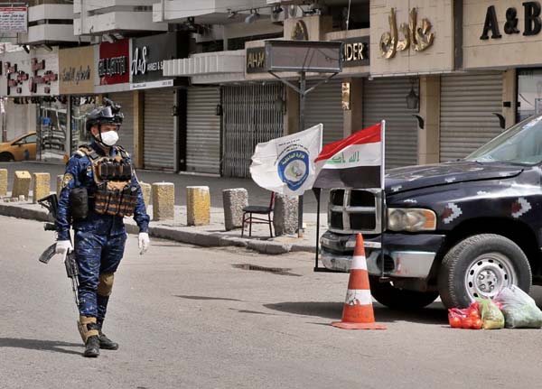 A federal policemanâ€™s a checkpoint near shops that are shuttered to help prevent the spread of the coronavirus, in Baghdad, Iraq on Thursday.