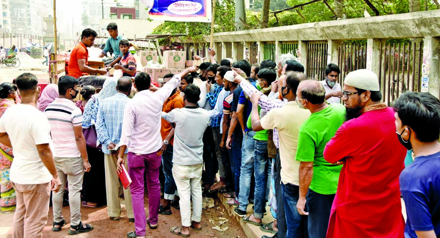 People form a queue for buying essential commodities from a TCB (Trading Corporation of Bangladesh) truck near Bangladesh Secretariat in the city on Saturday.