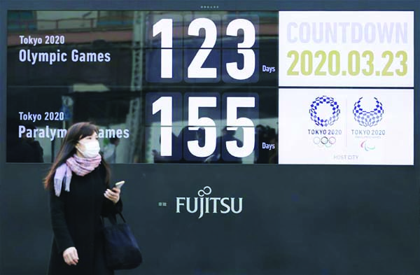 A woman wearing a face mask walks near a Tokyo 2020 Olympic and Paralympic Games countdown display in Shimbashi district, Tokyo, Japan on Monday. Japanese Prime Minister Shinzo Abe told the Parliament on Monday that the Tokyo Olympic Games could be postpo