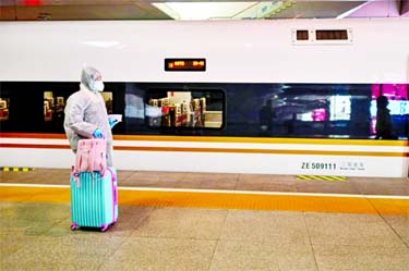 A woman wearing protective gear as she boards a train stopping at Wuhan, which has opened stations again to incoming passengers.