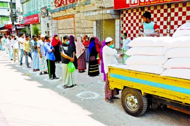 People lined up in distances to buy essentials from a truck, which is authorized by Food Directorate, amid coronavirus scare. This snap was taken from city's Badda area on Monday.