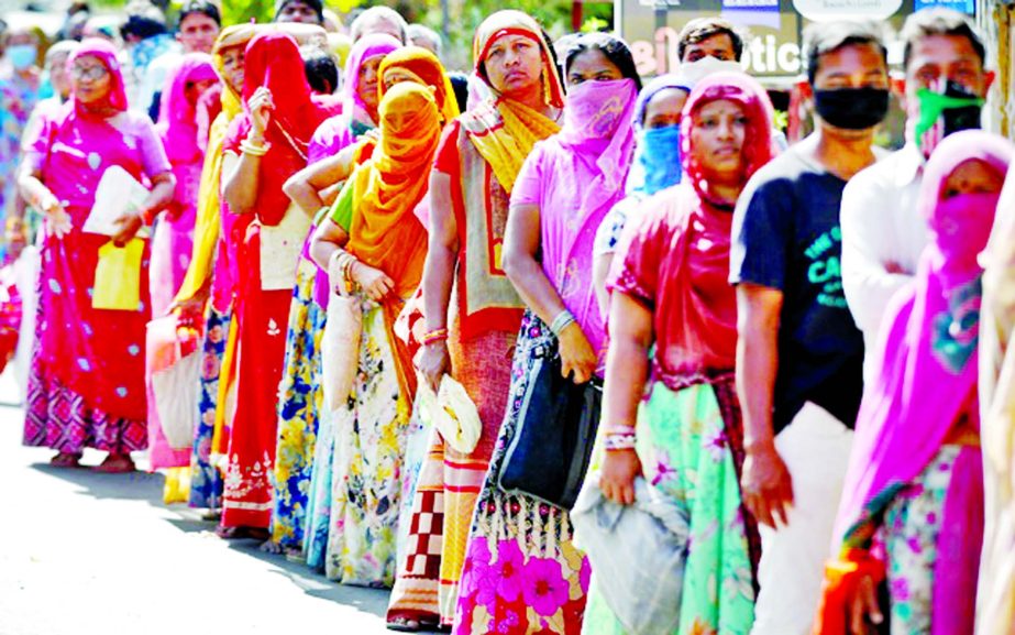 People stand in a queue as they wait for their turn to receive free food grains from a government controlled grains store during a 21-day nationwide lockdown to slow the spreading of coronavirus disease in Ahmedabad, India on Wednesday.