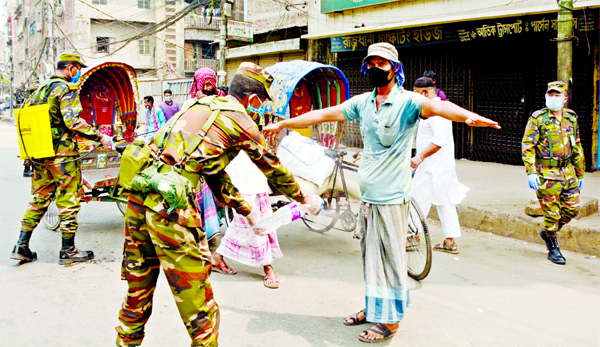 Army personnel are seen spraying germicide on the body of a rickshaw-puller fearing novel coronavirus. This picture was taken from English Road area on Sunday.