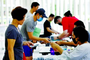 Residents receive free reusable masks distributed by the government at a community center, as stricter measures are announced to combat the outbreak of the coronavirus in Singapore on Sunday.