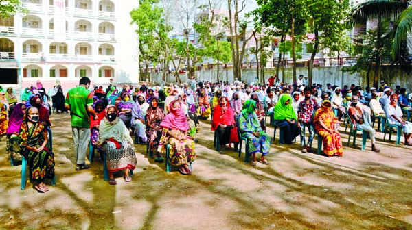 Relief materials being distributed with the assistance of Dhaka District Administration among the poor people keeping social distance in the city's Manda area on Monday.