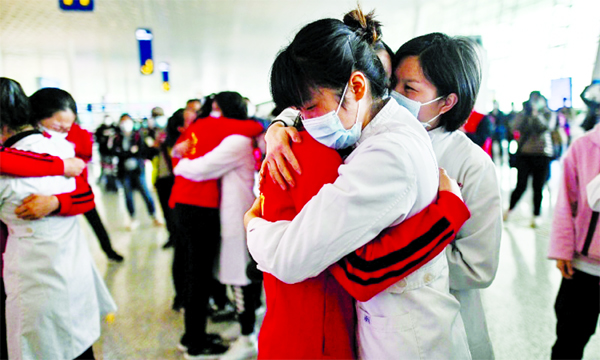 Medical staff from Jilin Province (in red) hug nurses from Wuhan after working together during the coronavirus outbreak on during a ceremony before leaving as Tianhe Airport is reopened in China's central Hubei province on Wednesday.