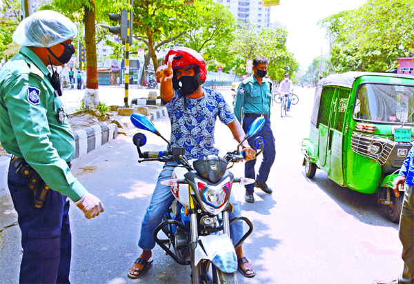 Police personnel intercept a motorcyclist roaming in streets without any reason defying lockdown imposed by government over coronavirus. This picture was taken from city's Mohammadpur area on Friday.