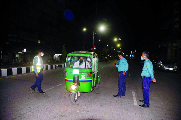 Police intercept a CNG Auto at a checkpoint in front of Modhumita Cinema Hall in Dhaka on Friday evening during lockdown in response to the outbreak of the coronavirus pandemic in the city.