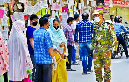 An army personnel asking people to maintain physical distance at the capital's Mouchack intersection in Dhaka on Saturday amid lockdown in the city due to coronavirus.