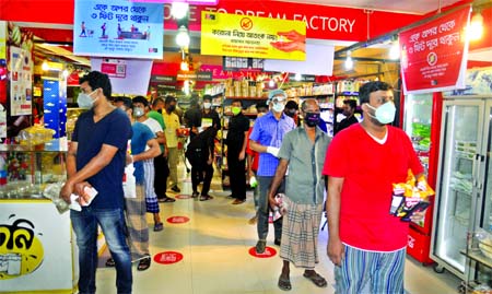 Customers crowd at an outlet of Sopno Super Shop at Nazimudddin Road in Dhaka on Sunday maintaining physical distance guideline amid outbreak of coronavirus.