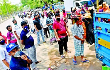 People line up and jostle each other to buy essential commodities from a TCB truck at Motijheel Ideal School in Dhaka on Monday putting the government social distancing order in jeopardy.