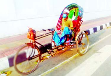 A rickshaw puller wearing face mask waits for passenger during shutdown in Dhaka on Wednesday.