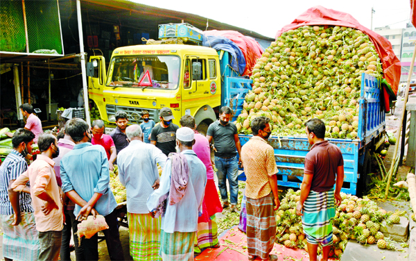 Traders gather in front of a truck loaded with pineapples in the city's Karwan Bazar Kitchen Market in Dhaka on Friday defying social distance practice.