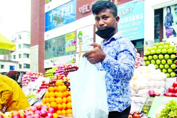 A shop owner serves his customer at a fruit shop in the city's Dhanmondi area on Friday following social distancing protocol.