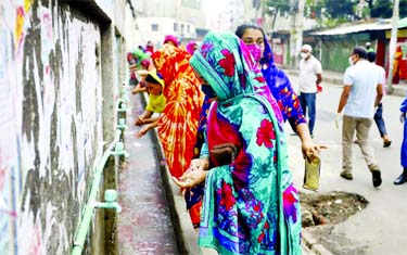 Garment workers wash hands with germicide mixed water at a factory in Mirpur on Tuesday maintaining safe distance among each other.