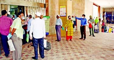 Customers, maintaining social distancing, stand inside a bank for their financial transactions during the nationwide lockdown in the wake of deadly coronavirus in Dhaka on Thursday.