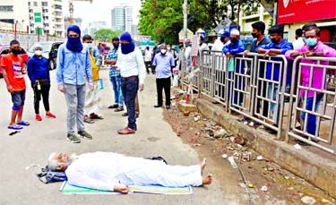 An old man suddenly becomes senseless on the road while waiting in a long queue to get treatment at the fever clinic of Bangabandhu Sheikh Mujib Medical University on Sunday amid rising infections of COVID-19 in Dhaka.