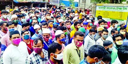 A large number of workers gather and jostle themselves in front of a factory gate at BSCIC industrial Zone in Narayanganj on Monday ignoring physical distancing protect.