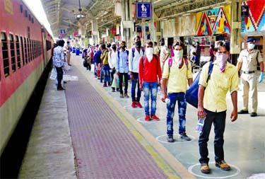 Migrant workers, who were stranded in the western state of Gujarat due to a lockdown imposed by the government to prevent the spread of coronavirus, maintain social distance as they stand in a queue to board a train that will take them to their home state