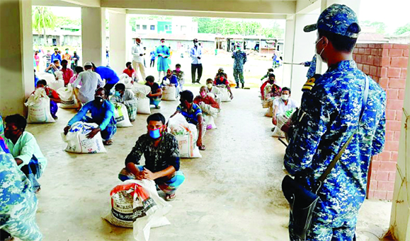 Navy personnel distributing relief goods among the poor and destitute people of Teknaf under Cox's Bazar district maintaining social distancy on Wednesday.