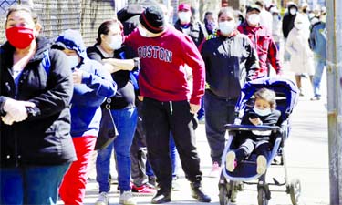 People wear masks out of concern for the coronavirus while standing in line outside a Salvati Army Food pantry in Chelsea, Massachusetts on Wednesday.